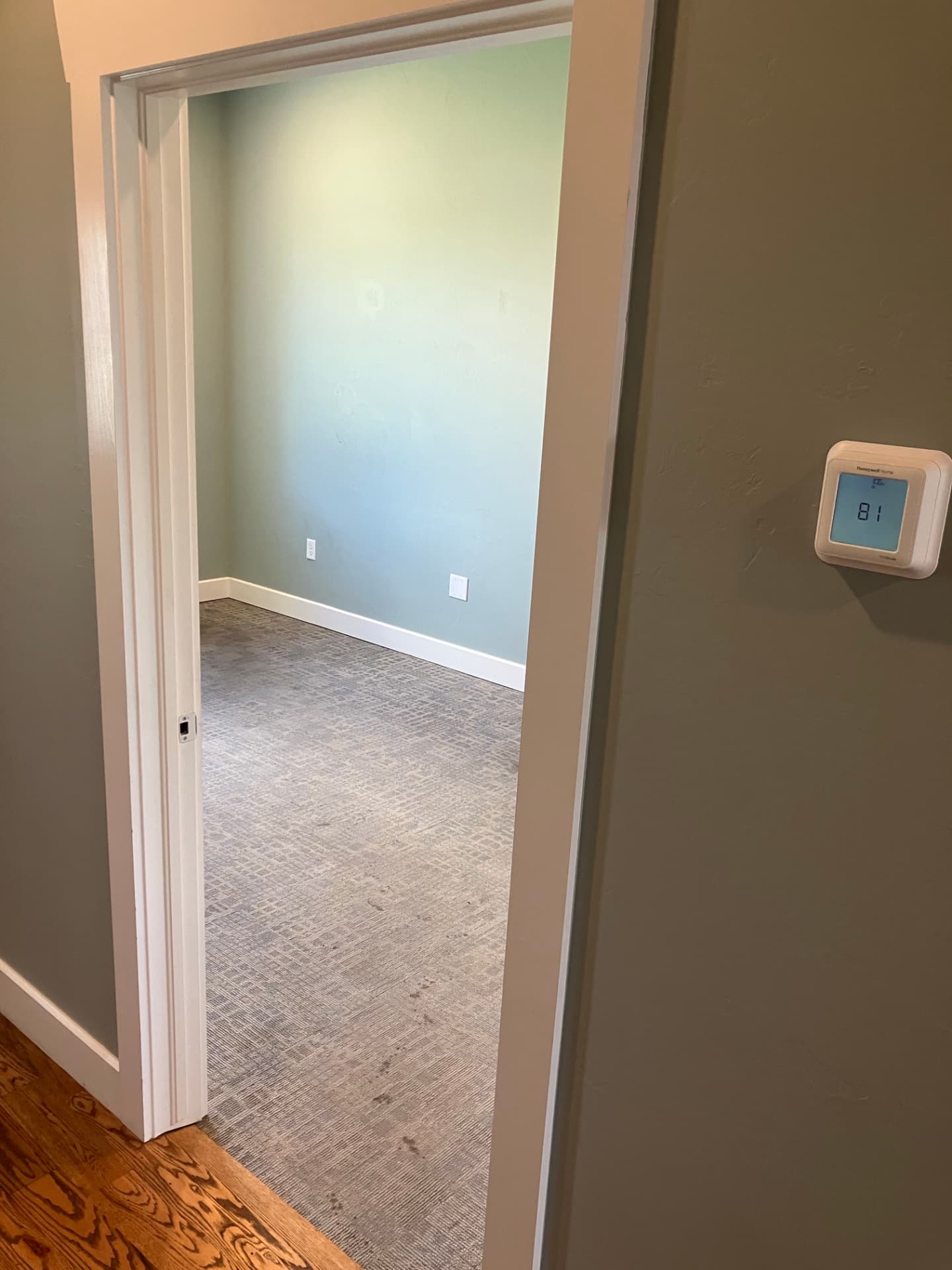 Suite B hallway with a programmable thermostat and a doorway to a carpeted office